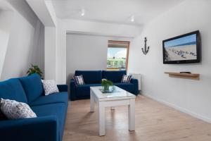 ein Wohnzimmer mit einem blauen Sofa und einem Tisch in der Unterkunft Apartament Biała Kotwica in Jastrzębia Góra