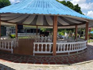 a pavilion with white chairs and a blue roof at Hotel Campestre Kosta Azul in Villavicencio