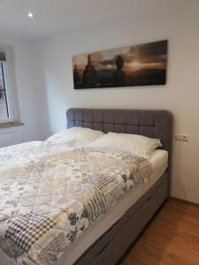 Una cama en un dormitorio con un cuadro en la pared. en Ausseeerland, en Bad Aussee