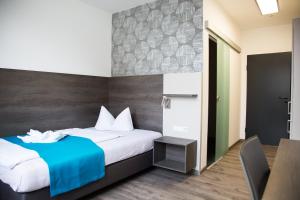 a bedroom with a bed with a blue blanket and a table at Hotel im Kaiserpark in Meiningen