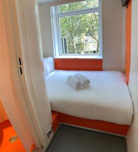 a white teddy bear sitting on top of a white bed at easyHotel South Kensington in London
