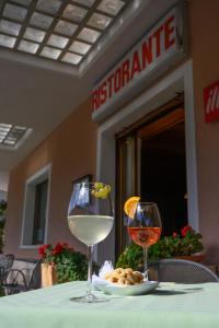 einen Tisch mit zwei Gläsern Wein und einem Teller Essen in der Unterkunft Hotel Dolomiti in Vattaro