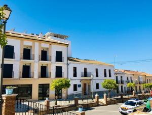 a white building with black windows on a street at Apartamentos La Laguna in Fuente de Piedra