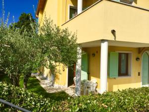 ペスキエーラ・デル・ガルダにあるAppartamenti agli Uliviの緑の扉と木々のある黄色い家
