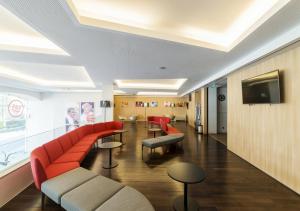 a waiting room with a red couch and a tv at Moov Hotel Porto Centro in Porto