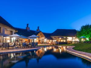 a pool with chairs and umbrellas in front of a building at Ivory Tree Game Lodge in Pilanesberg