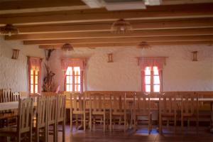 een eetkamer met tafels, stoelen en ramen bij Tourist Farm Apartments Lovrec in Jiršovci