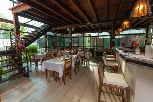 a restaurant with white tables and chairs and windows at Pousada Villa da Mata in São Miguel Arcanjo