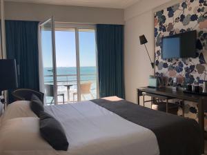 レ・サ​​ーブル・ドロンヌにあるHotel & Spa Les Roches Noiresのベッド付きのホテルルームで、海の景色を望めます。