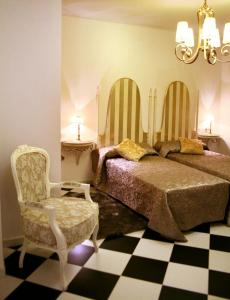 a bedroom with a bed and a chair and a chandelier at Hostal Mesón Castilla in Sigüenza