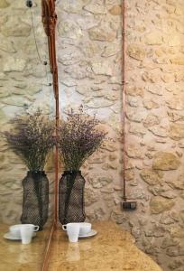 two vases with flowers on a table with a stone wall at Hostel Numero Trece in Alicante
