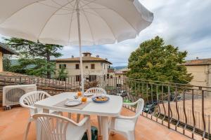 une table blanche et des chaises avec un parasol sur un balcon dans l'établissement Casa Irene, à San Gimignano