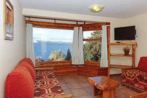 un salon avec une grande fenêtre avec vue sur l'eau dans l'établissement Apart Altos Del Nahuel, à San Carlos de Bariloche