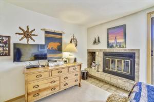a living room with a fireplace and a wooden dresser at Cedar Lodge 309 in Frisco