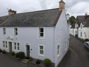 a white house with a black roof on a street at Vollie House with Hot Tub, Sauna & Log Burner in Penpont