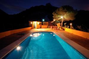 una piscina por la noche con luces encendidas en El Capricho de Almadan en Ojén