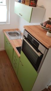 een groene keuken met een wastafel en een magnetron bij Appartement Waldenser in Bad Homburg vor der Höhe