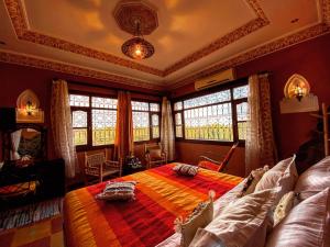 a bedroom with a large bed and two windows at Riad Chay & Boutique in Ouarzazate