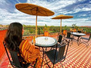 a woman sitting at a table with tables and umbrellas at Riad Chay & Boutique in Ouarzazate