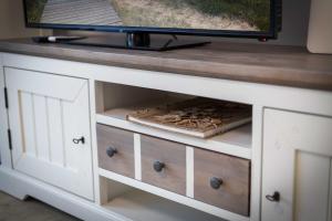 a tv on top of a white cabinet with wooden drawers at Alte Waescherei _9461_ in List