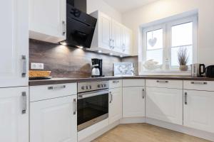 uma cozinha com armários brancos e um forno com placa de fogão em Alte Waescherei _9461_ em List