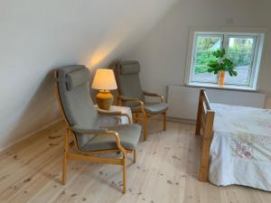 ein Schlafzimmer mit 2 Stühlen, einem Bett und einem Fenster in der Unterkunft Lohalshygge in Tranekær