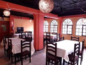 a dining room with white tables and chairs and windows at HOSTAL VISTA AMAZONAS in Quito