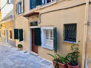 a building with green shutters on a street at Grandma’s old town house in Corfu Town