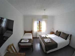 a bedroom with two beds and a window and a chair at Hostería Bärenhaus in San Martín de los Andes