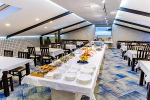a long dining room with white tables and chairs at Hotel Biss in Zenica