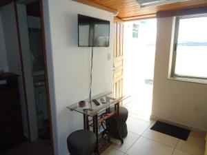 Habitación con mesa de cristal y TV en la pared. en APARTAMENTOS ALTOS DA GRUPIARA - DIAMANTINA/MG, en Diamantina