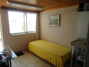 Un dormitorio con una cama amarilla y una ventana en APARTAMENTOS ALTOS DA GRUPIARA - DIAMANTINA/MG, en Diamantina