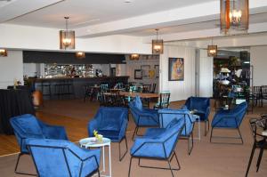 a room with blue chairs and tables and a bar at Hotel Cap-aux-Pierres in L'Isle-aux-Coudres