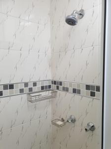 y baño con ducha y paredes de mármol blanco. en Angela's Place, en Durban