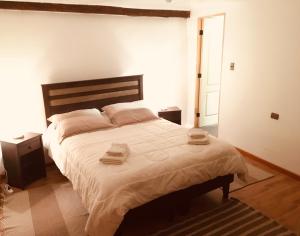 1 dormitorio con 1 cama grande y 2 toallas. en La Casa del Pueblo Hostal, en San Pedro de Atacama