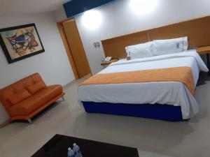 a bedroom with a large bed and a chair at Hotel CEO in Morelia