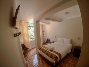 um quarto com uma grande cama branca e uma janela em RUMIQOLQA Machupicchu Hotel em Machu Picchu