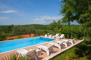 una piscina con sillas blancas y una piscina en Mugeba Club Residence, en Poreč