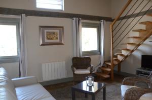 a living room with a white couch and a staircase at Gite La Suite Ducale Chateau La Roche Racan in Saint-Paterne-Racan