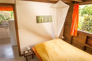 a bedroom with a bed with an orange blanket and a window at Les jardins de Pointe Noire in Pointe-Noire