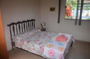 a bedroom with a bed with a floral comforter at Skandalo Pub Pousada in Rio das Ostras