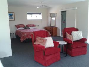 um quarto com uma cama e 2 cadeiras em Moana Vista em One Tree Point