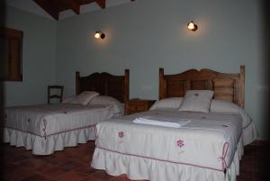 1 dormitorio con 2 camas con sábanas blancas y flores. en Casa Rural Las Encinas, en Marchena