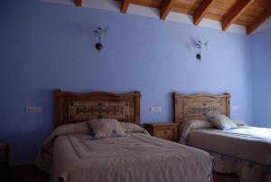 1 dormitorio con 2 camas y pared azul en Casa Rural Las Encinas, en Marchena