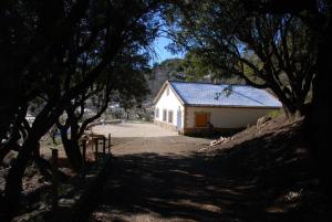 a white building with a blue roof and some trees at Casa Rural Las Encinas in Marchena