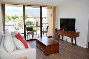 a living room with a white couch and a flat screen tv at Pacific Shores A406 in Kihei