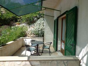 a table and chairs on a porch with a green door at Apartments Brane - 150m from sea in Bol