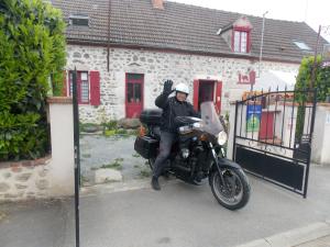 a person sitting on a motorcycle in front of a house at Les Maitres Sonneurs in Huriel