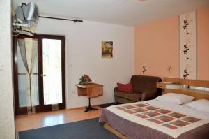 a bedroom with a bed and a chair and a television at Apartments Ruža - free parking in Supetarska Draga