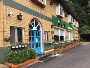 een gebouw met een blauwe deur en bloemen voor de deur bij Alishan MinYue Hotel in Fengshan